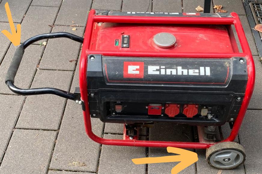 Ein Einhell TC-PG Notstromaggregat ist auf Rollen und der Schiebegriff ist ausgeklappt.